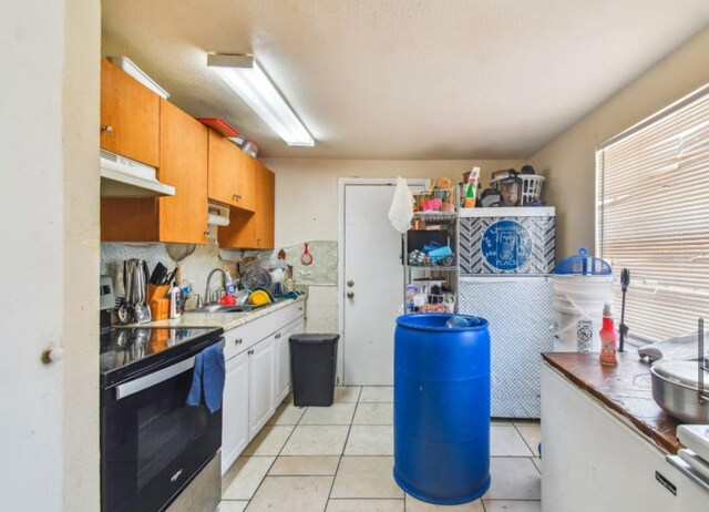 kitchen with tasteful backsplash, exhaust hood, sink, electric range, and light tile patterned flooring