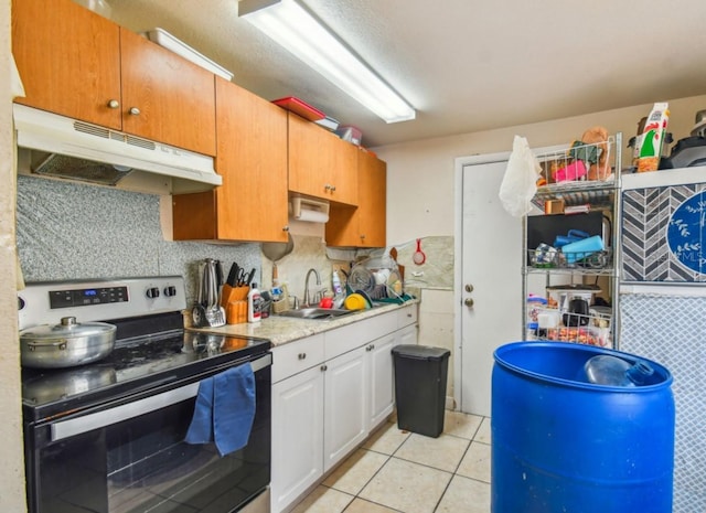 kitchen with tasteful backsplash, sink, light tile patterned floors, white cabinets, and stainless steel electric range