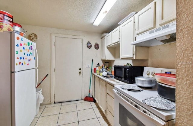 kitchen with light tile patterned floors, white appliances, a textured ceiling, and white cabinetry