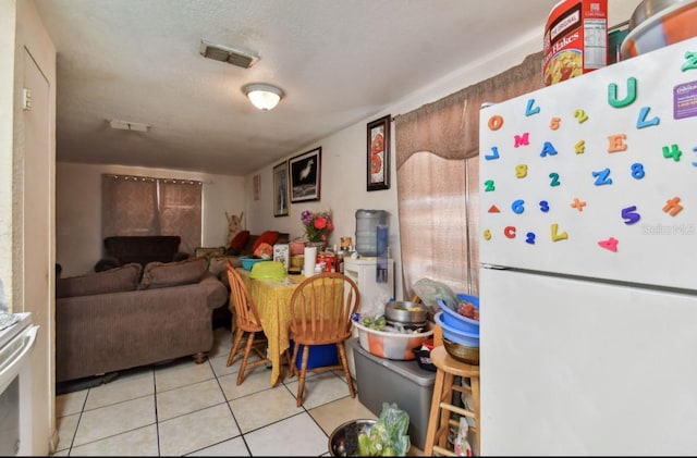 kitchen with light tile patterned floors, a textured ceiling, and white fridge