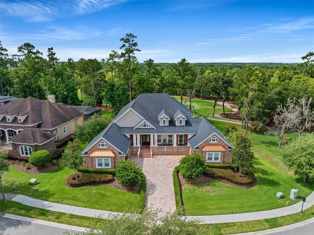 view of front of house with a porch, brick siding, driveway, roof with shingles, and a front yard