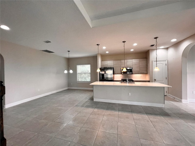 kitchen with sink, an island with sink, pendant lighting, light tile patterned flooring, and appliances with stainless steel finishes