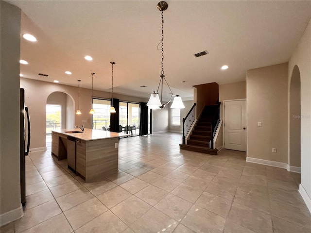 kitchen featuring pendant lighting, a large island with sink, sink, light tile patterned floors, and stainless steel refrigerator