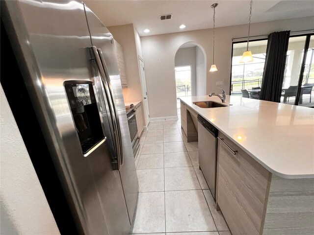 kitchen featuring stainless steel appliances, sink, light tile patterned floors, hanging light fixtures, and a large island