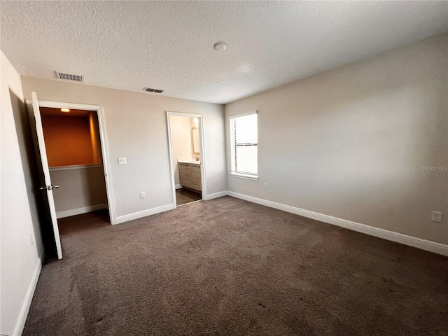 unfurnished bedroom with connected bathroom, a closet, a textured ceiling, and dark colored carpet