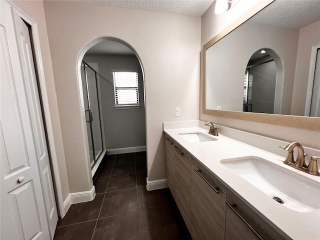 bathroom featuring tile patterned flooring, vanity, a shower with door, and a textured ceiling