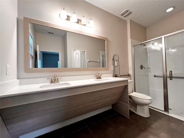 bathroom with tile patterned floors, vanity, a shower with shower door, and toilet