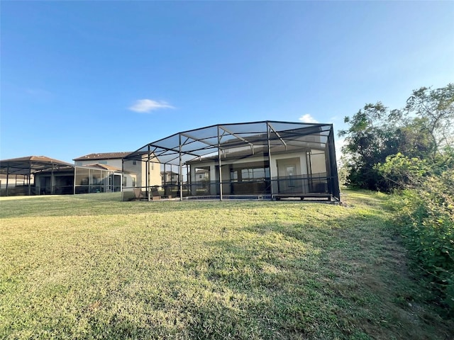 back of house with a lawn and glass enclosure