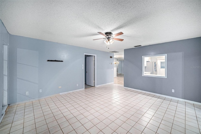 empty room with a textured ceiling, ceiling fan, and light tile patterned flooring