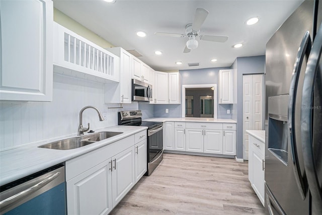 kitchen featuring appliances with stainless steel finishes, light hardwood / wood-style floors, sink, white cabinets, and ceiling fan