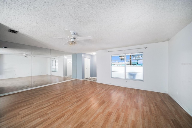 interior space featuring ceiling fan, wood-type flooring, a textured ceiling, and a healthy amount of sunlight