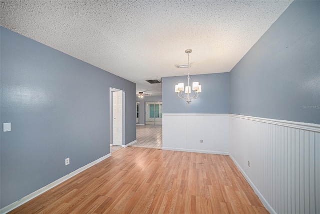 unfurnished dining area featuring a textured ceiling, ceiling fan with notable chandelier, and light tile patterned flooring