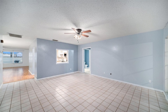 spare room featuring a textured ceiling, ceiling fan, and light tile patterned floors