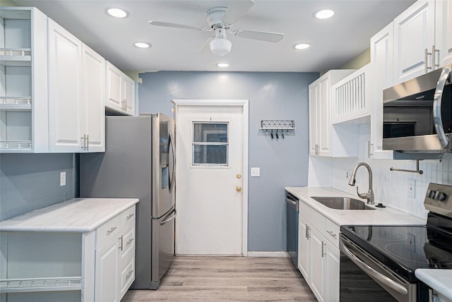 kitchen featuring sink, white cabinetry, appliances with stainless steel finishes, light hardwood / wood-style flooring, and ceiling fan