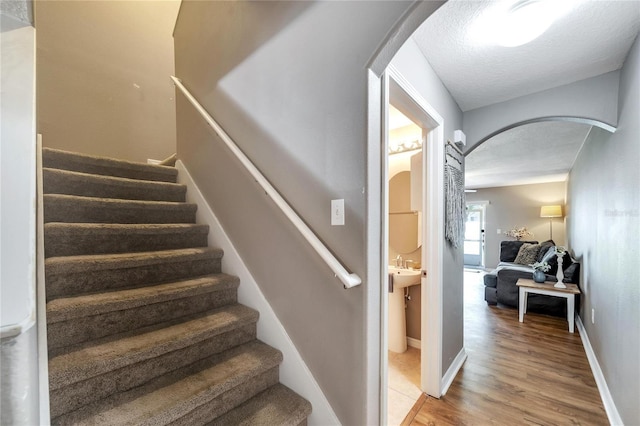 staircase with hardwood / wood-style floors and a textured ceiling