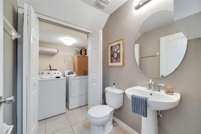 bathroom featuring tile patterned floors, toilet, washing machine and dryer, and vaulted ceiling