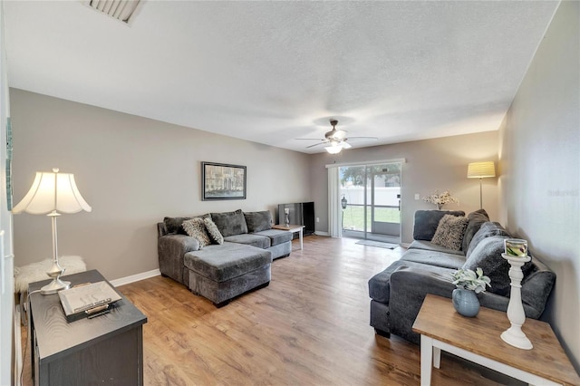 living room with ceiling fan, light hardwood / wood-style floors, and a textured ceiling