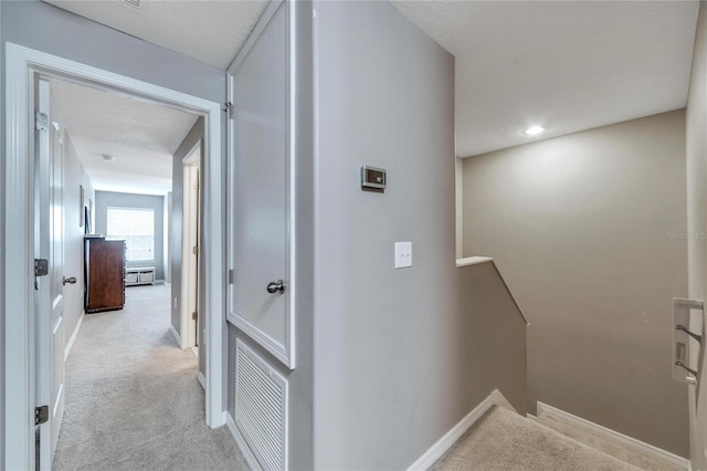 hallway featuring light carpet and a textured ceiling