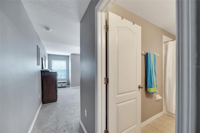 hallway with light carpet and a textured ceiling