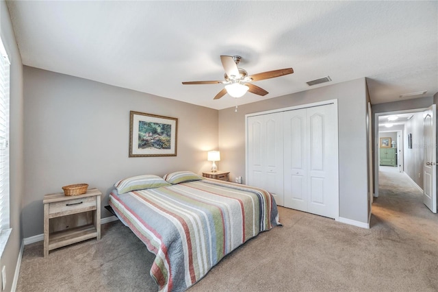 bedroom with ceiling fan, light carpet, and a closet