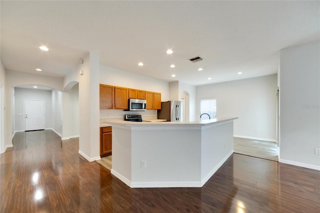 kitchen featuring sink, a center island with sink, dark wood-type flooring, and appliances with stainless steel finishes