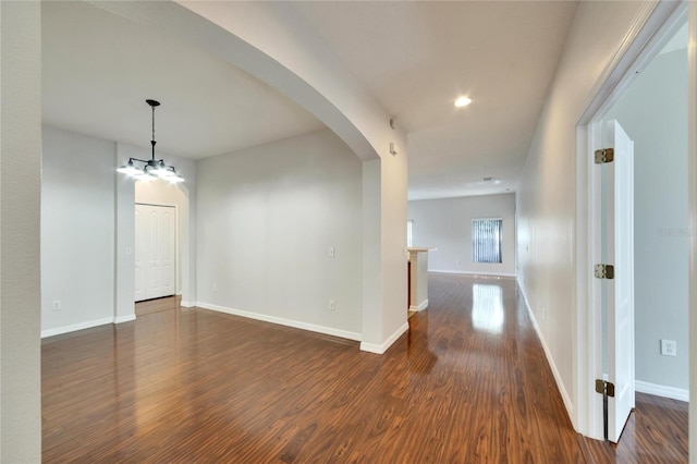 spare room with an inviting chandelier and dark wood-type flooring