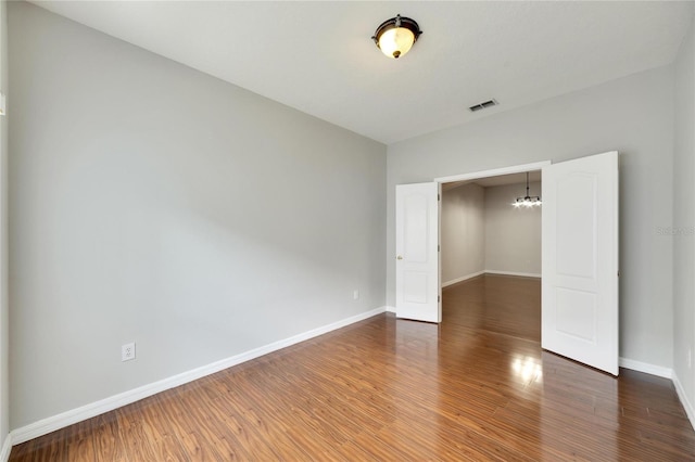 unfurnished bedroom featuring dark wood-type flooring and a chandelier