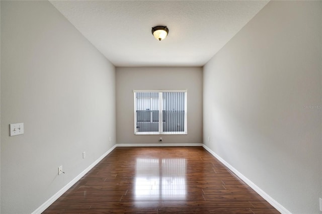 empty room with a textured ceiling and dark hardwood / wood-style floors