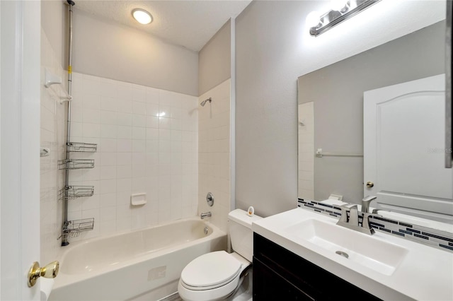 full bathroom with a textured ceiling, vanity, toilet, and tiled shower / bath