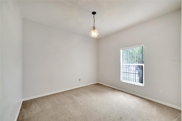 spare room featuring carpet and a notable chandelier