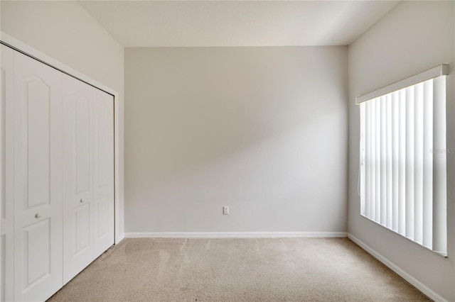 unfurnished bedroom featuring a closet and light colored carpet