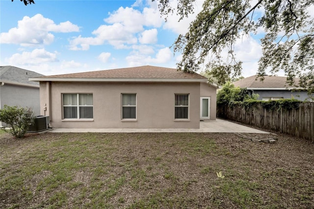 rear view of property with cooling unit, a patio area, and a lawn