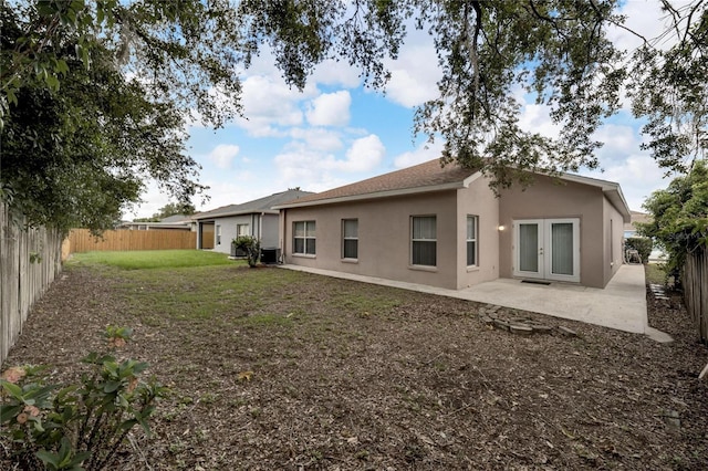 back of property with a lawn, cooling unit, a patio, and french doors