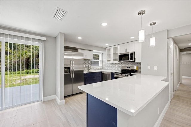 kitchen with backsplash, white cabinets, hanging light fixtures, kitchen peninsula, and stainless steel appliances