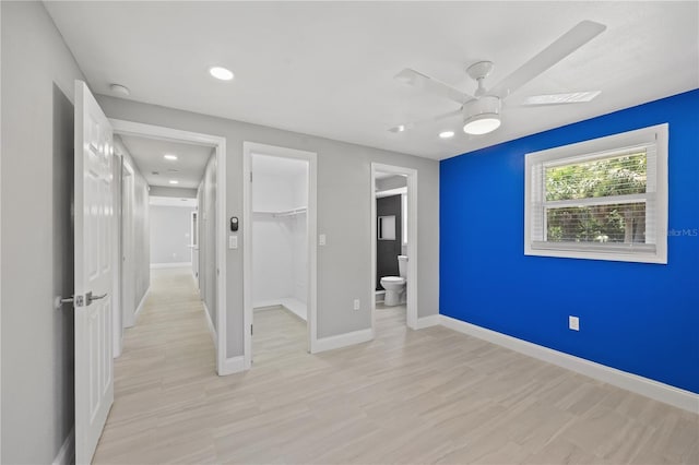 unfurnished bedroom featuring connected bathroom, a spacious closet, ceiling fan, a closet, and light wood-type flooring