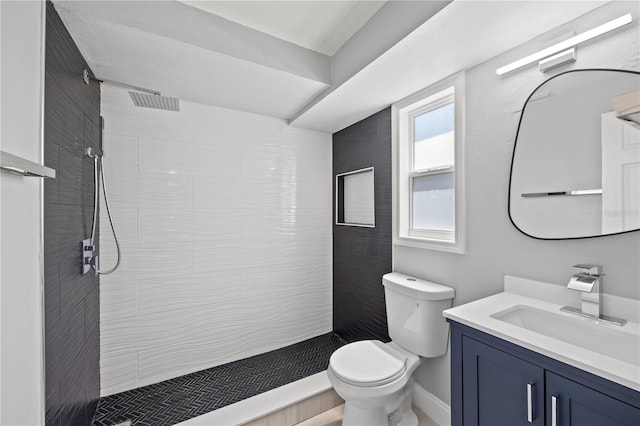 bathroom with a tile shower, vanity, and toilet