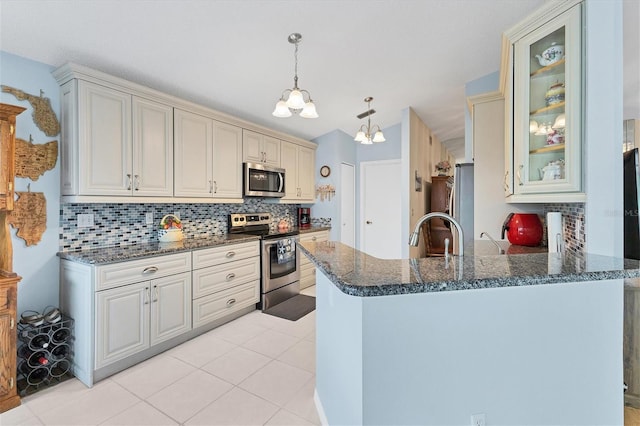 kitchen featuring light tile patterned floors, kitchen peninsula, stainless steel appliances, decorative backsplash, and pendant lighting