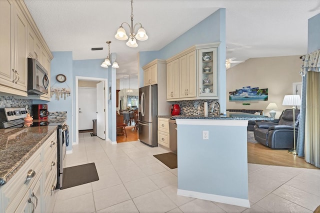 kitchen with cream cabinetry, decorative backsplash, light wood-type flooring, vaulted ceiling, and appliances with stainless steel finishes