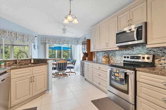 kitchen with light tile patterned floors, stainless steel appliances, a sink, cream cabinetry, and decorative backsplash