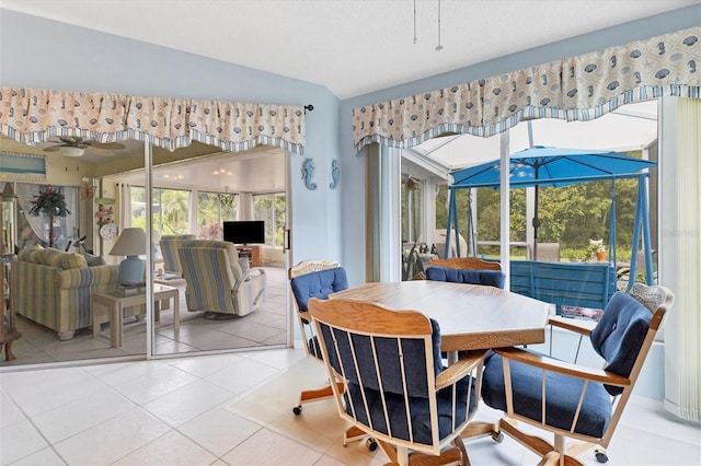 dining area featuring lofted ceiling, ceiling fan, tile patterned flooring, and a sunroom