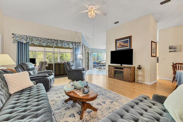 living area featuring visible vents, a ceiling fan, vaulted ceiling, wood finished floors, and baseboards