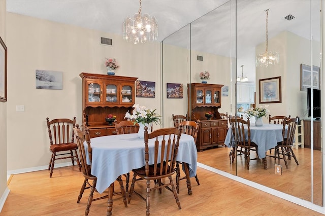 dining room with an inviting chandelier, a high ceiling, and light hardwood / wood-style flooring