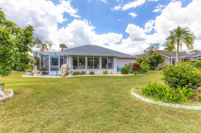 rear view of house with a yard, a pool, and a lanai