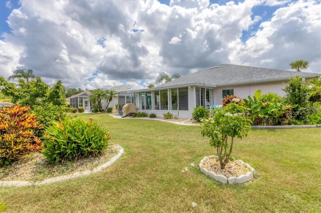 rear view of property featuring a lawn, a sunroom, and stucco siding