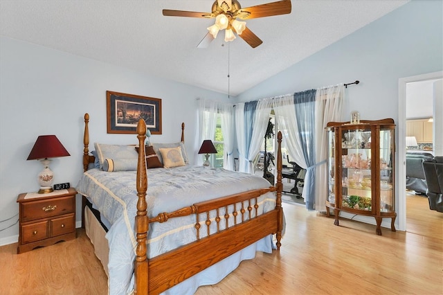 bedroom featuring lofted ceiling, a textured ceiling, a ceiling fan, and light wood-style floors