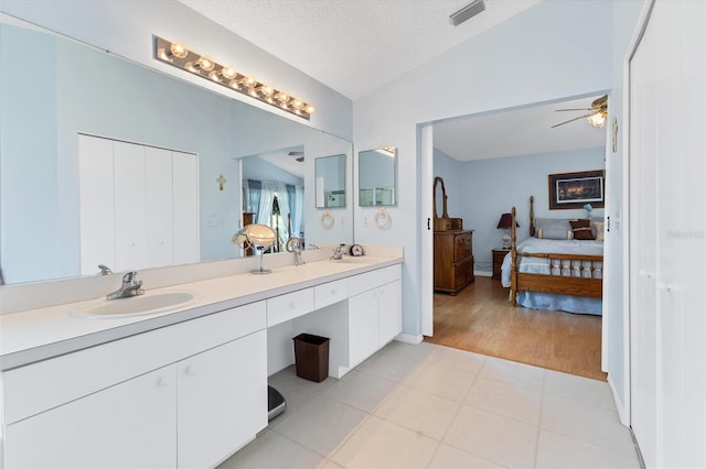 bathroom with tile patterned floors, ceiling fan, dual bowl vanity, a textured ceiling, and lofted ceiling