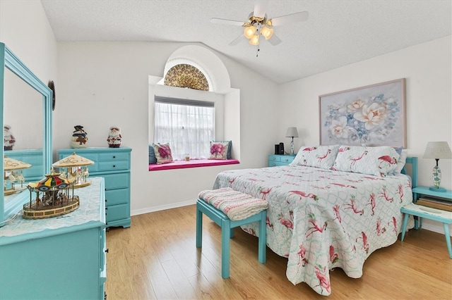 bedroom featuring light hardwood / wood-style floors, vaulted ceiling, a textured ceiling, and ceiling fan