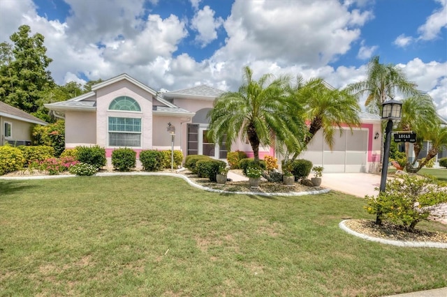 view of front of home with an attached garage, a front lawn, concrete driveway, and stucco siding