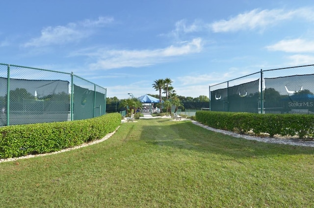 view of yard with a tennis court and fence