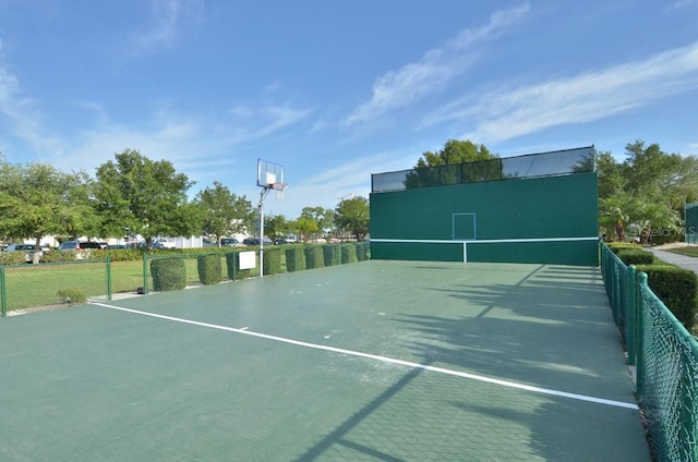 view of tennis court with community basketball court and fence